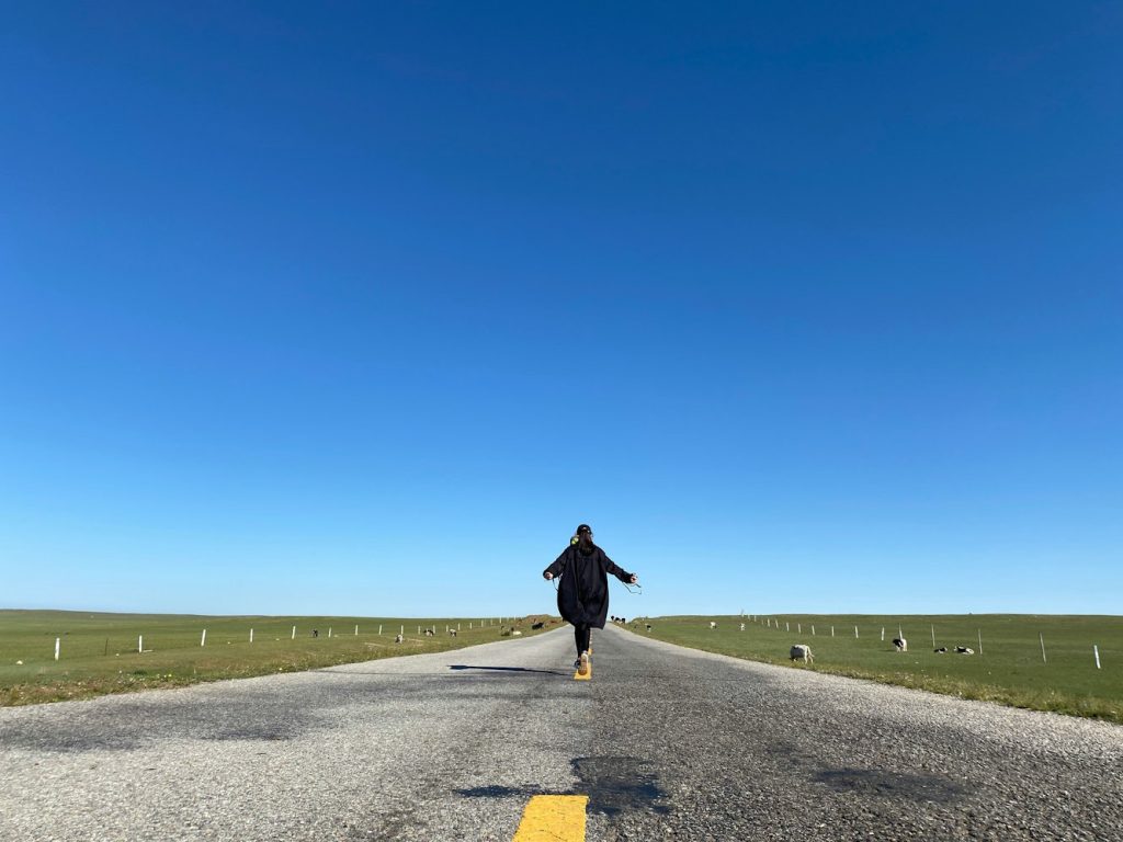 Person running down middle of rural road, wide open sky, cows on side of road by Yanping Ma via Unsplash